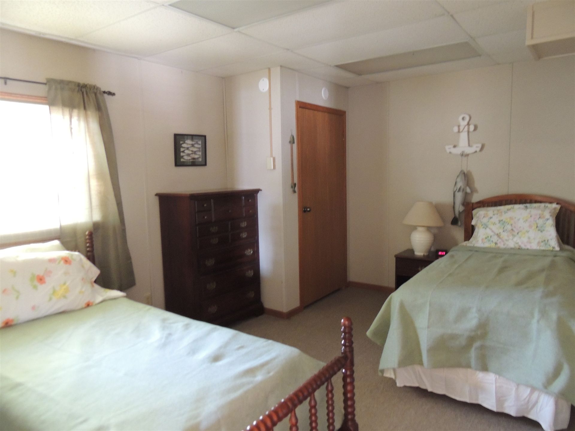 Bedroom with two twin beds, a dresser, window light, and a wooden door.