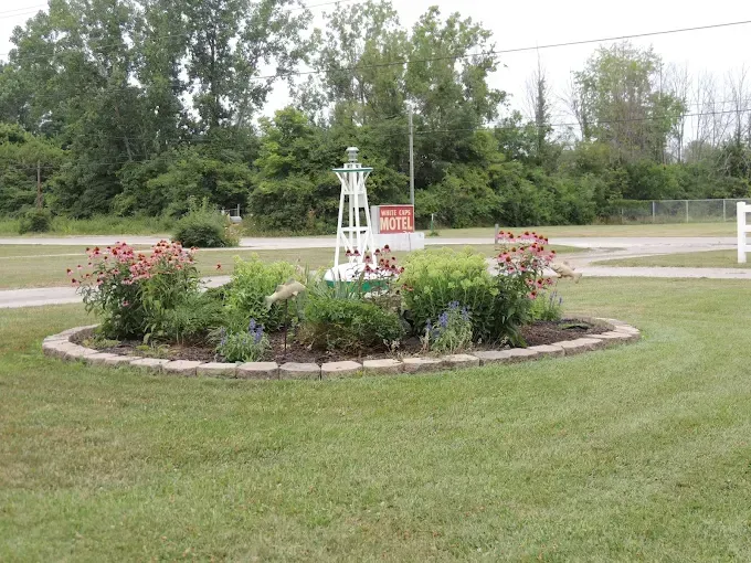 Circular flower bed with pink roses and a white garden trellis in a grassy park