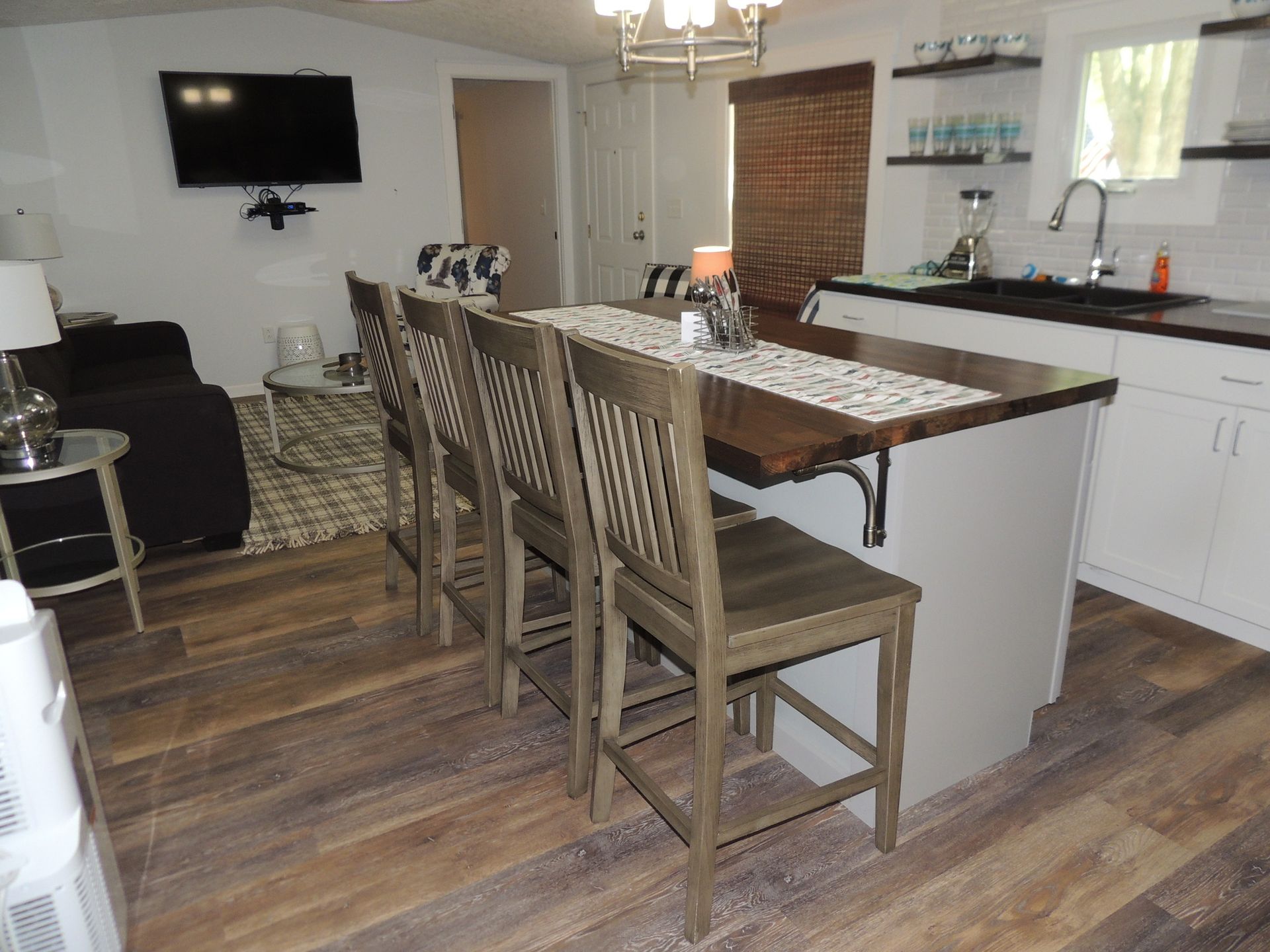 Open-concept kitchen and dining area with island, wood table, and wall-mounted TV