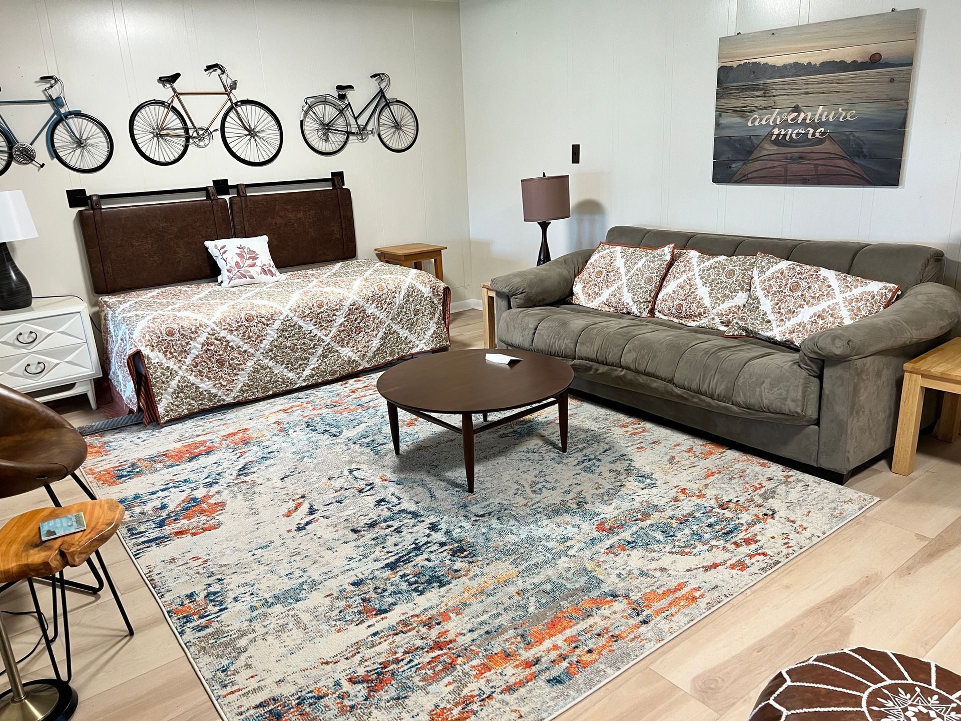 Cozy living room with bed, sofa, coffee table, bicycle wall art, and large patterned rug