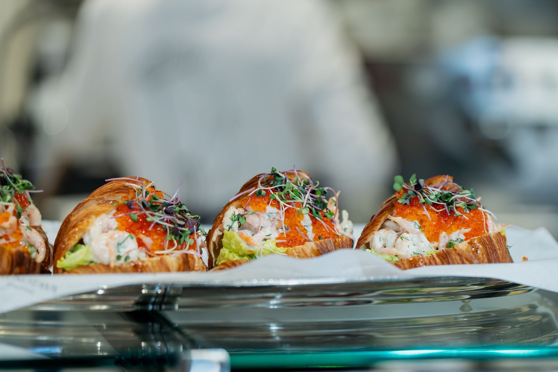 Plated gourmet appetizers topped with herbs and sauce on a glass table at a restaurant