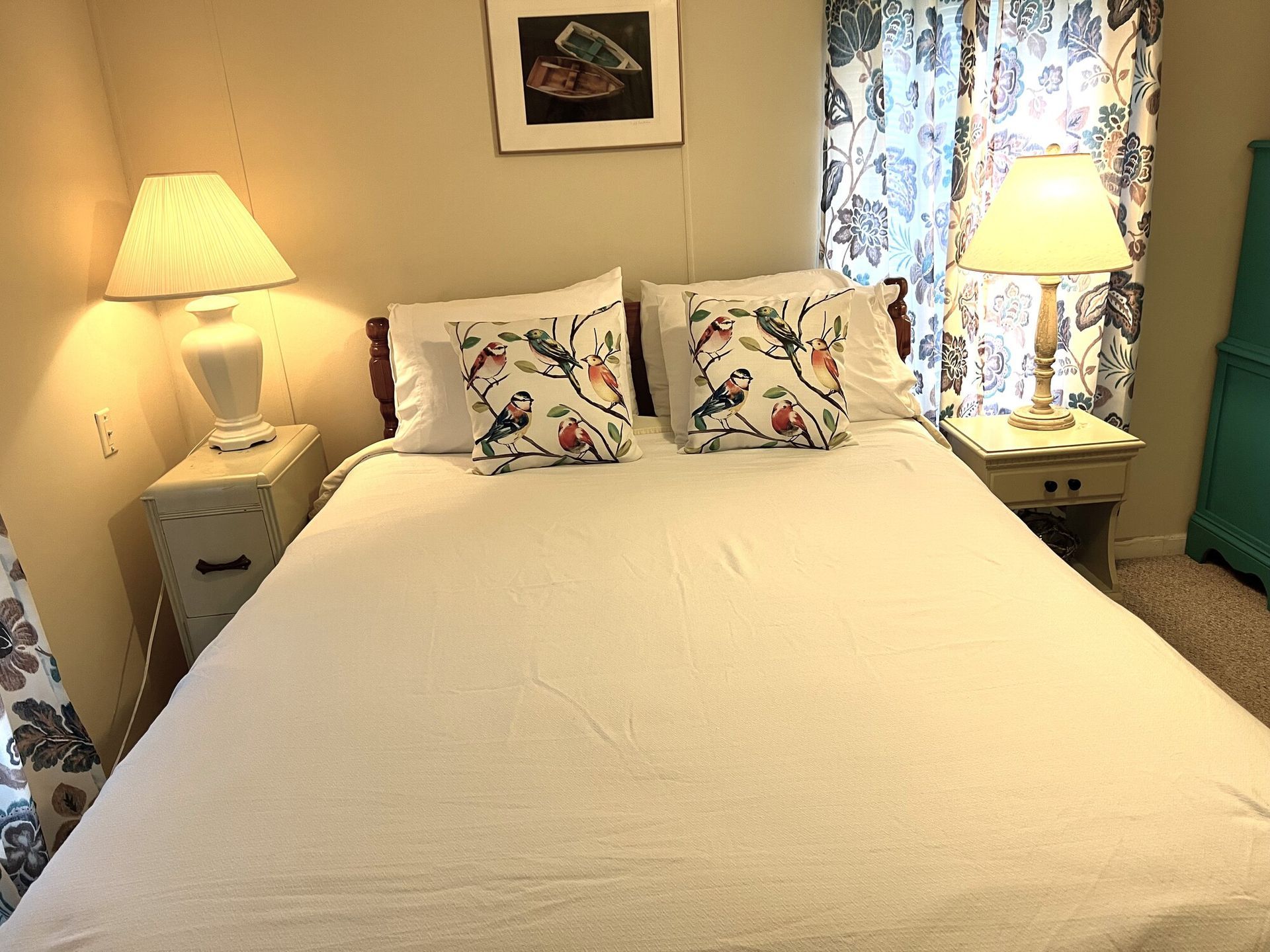 Cozy bedroom with a neatly made bed, floral pillows, and two lit bedside lamps