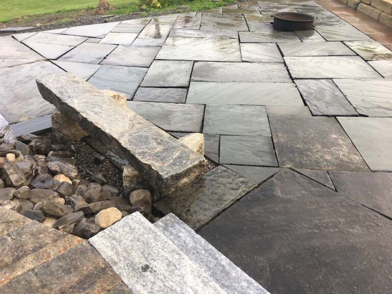 Stone patio with water feature and fire pit.