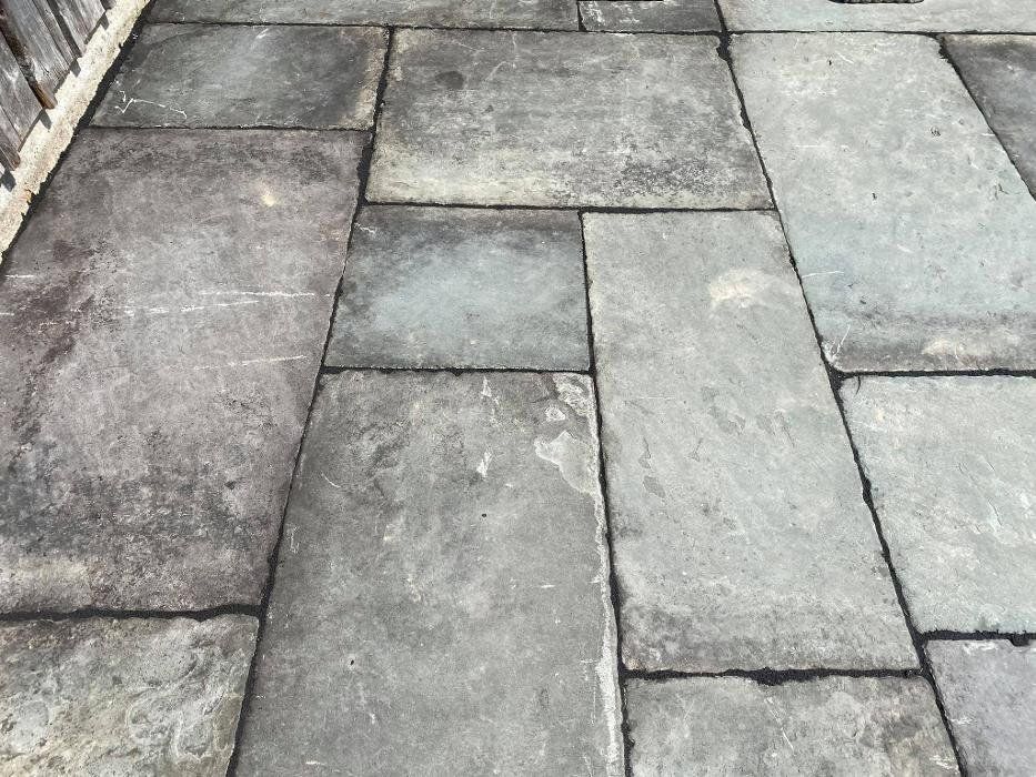 Gray stone patio pavers with dark grout, outdoors.