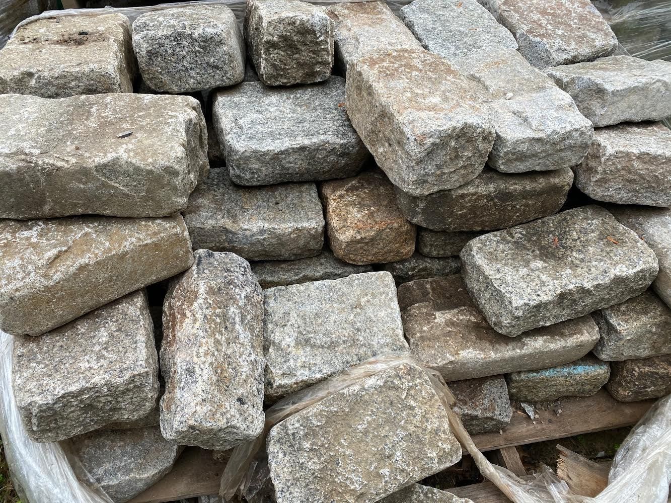 Pile of gray and tan rectangular cobblestones.