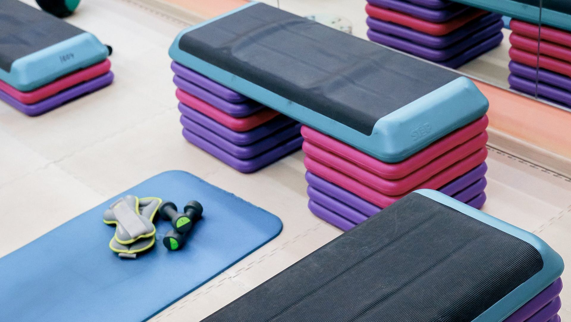 Step exercise equipment along with a mat and weights on the floor.