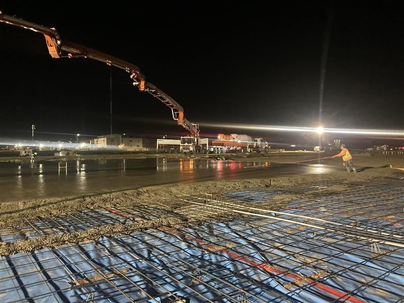 A bulldozer is pouring concrete into a pile of dirt.