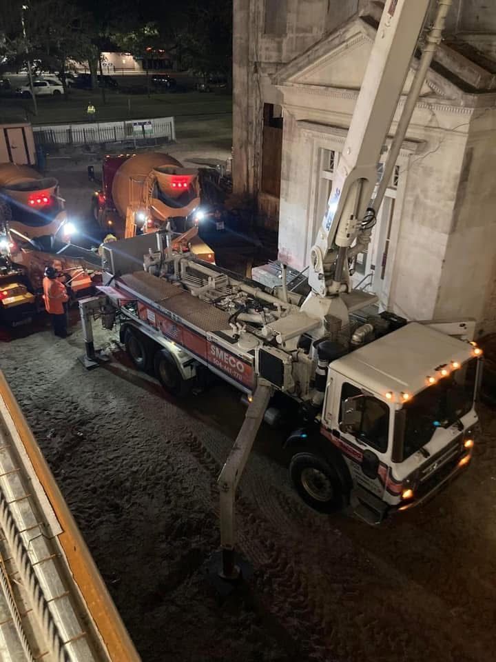 A concrete pump is pouring concrete on a construction site.