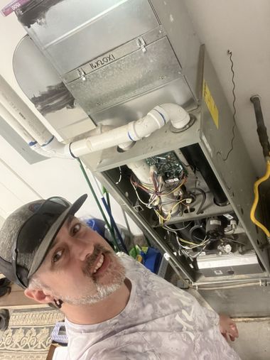 Man in a hard hat standing beside exposed ceiling HVAC and plumbing equipment, looking at the camera.