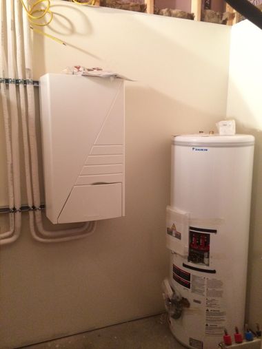 Water heater and wall-mounted utility box with pipes in a small basement utility area