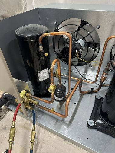 Refrigeration compressor and copper tubing inside an outdoor HVAC unit.