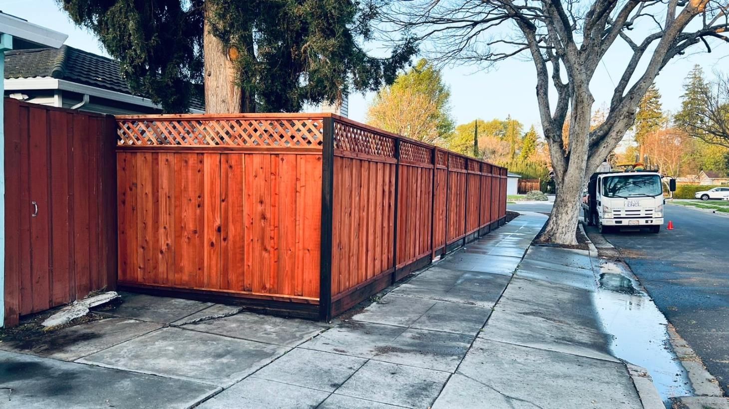 Spacious green lawn bordered by a new wooden fence, adorned with sturdy stone brick pillars.