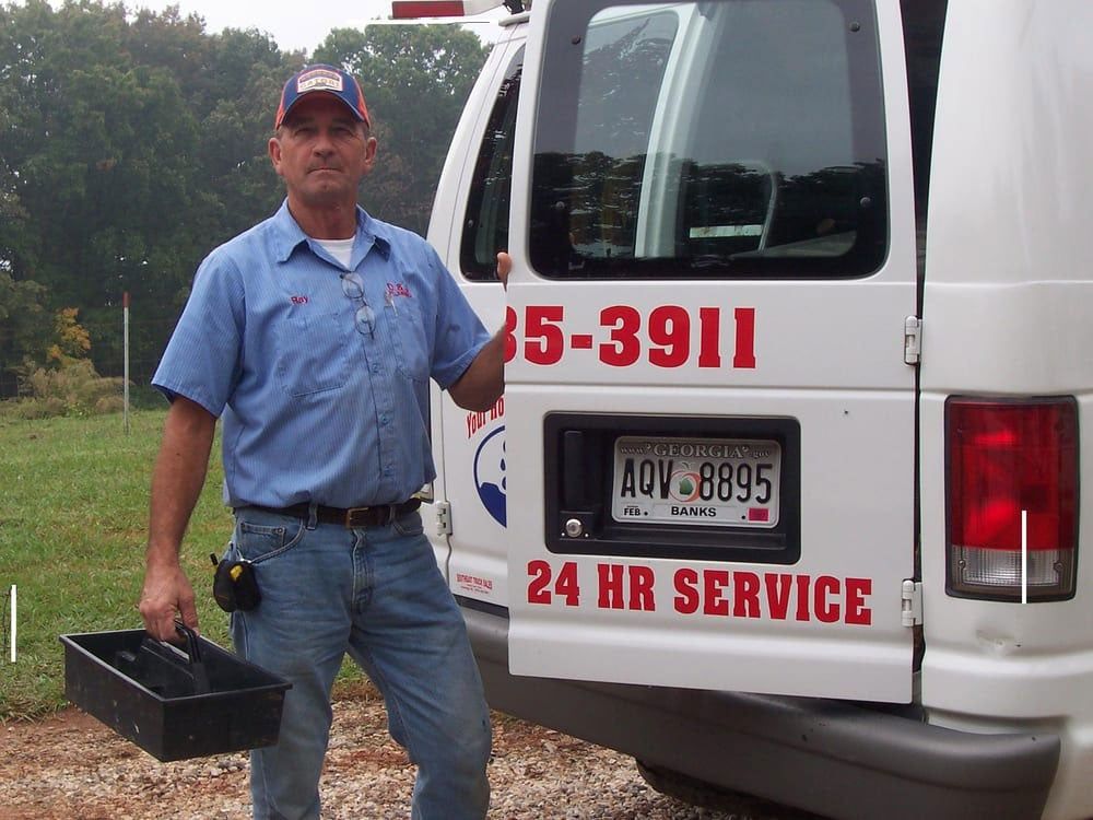 Professional plumber standing next to D & J Plumbing 24hr service truck