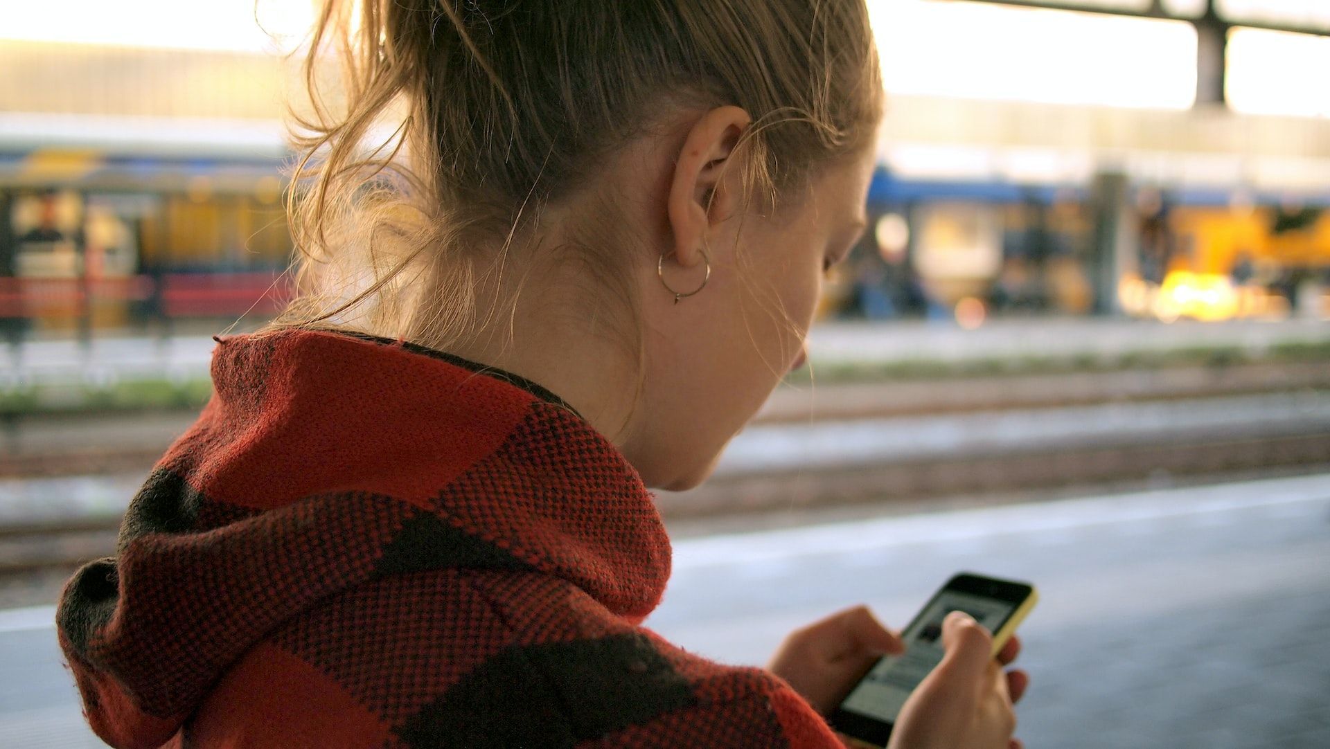 A woman using a mobile app on her phone at a train station.