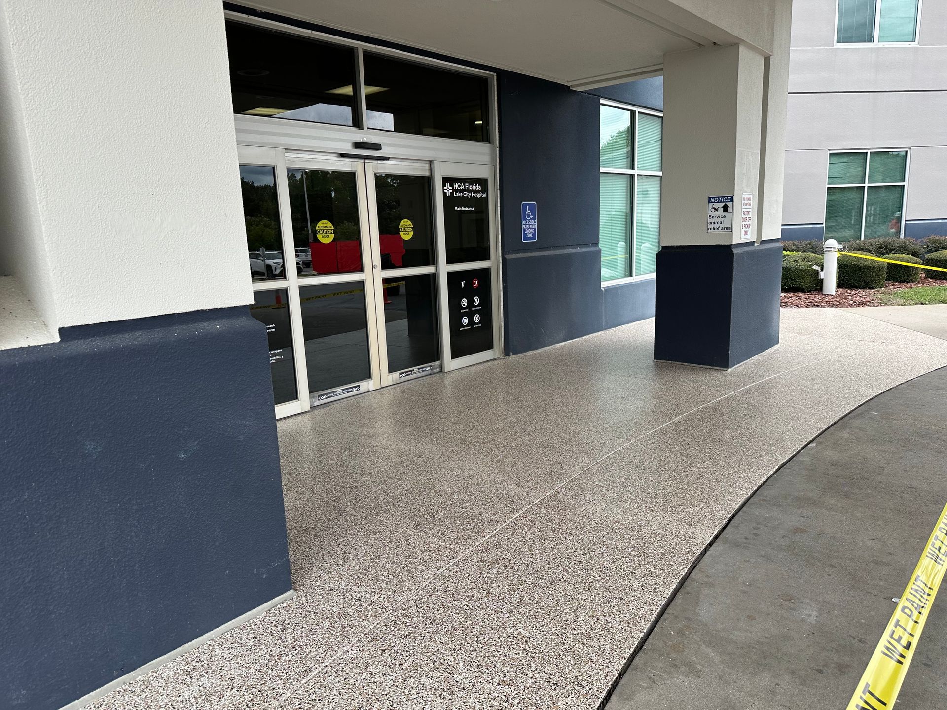 Entrance with automatic doors, grey speckled floor, and navy blue pillars.