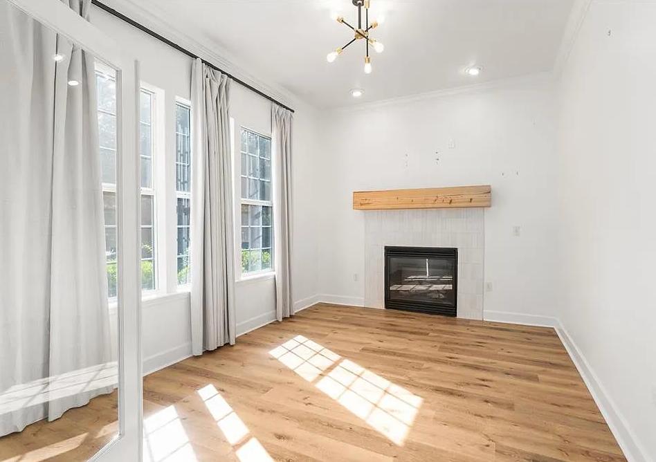 Two workers in white overalls spraying paint in a room. One on a ladder, the other holding a hose.