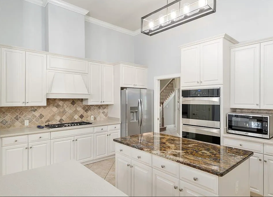 Modern kitchen with black cabinets, white countertops, and a central island with black stools.
