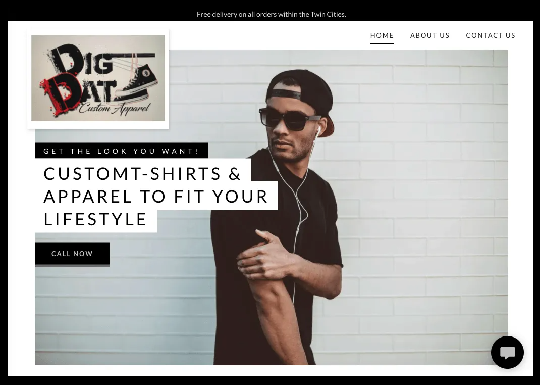 A man wearing a hat and sunglasses is standing in front of a white brick wall.