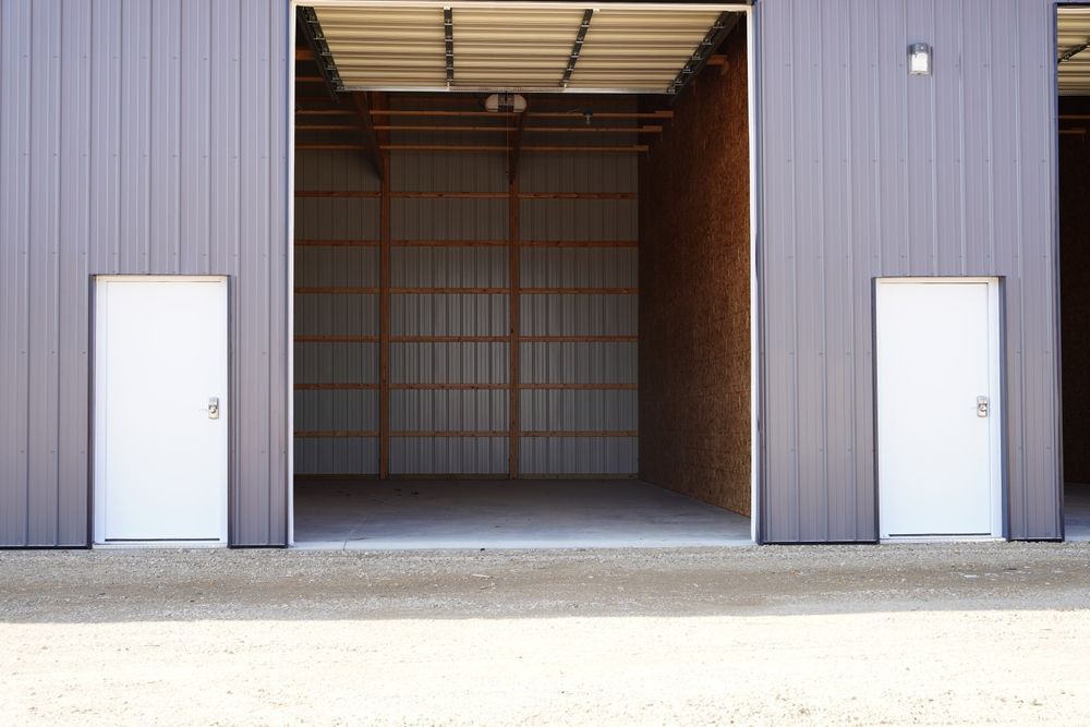 Open warehouse bay with two white doors on a gray metal building