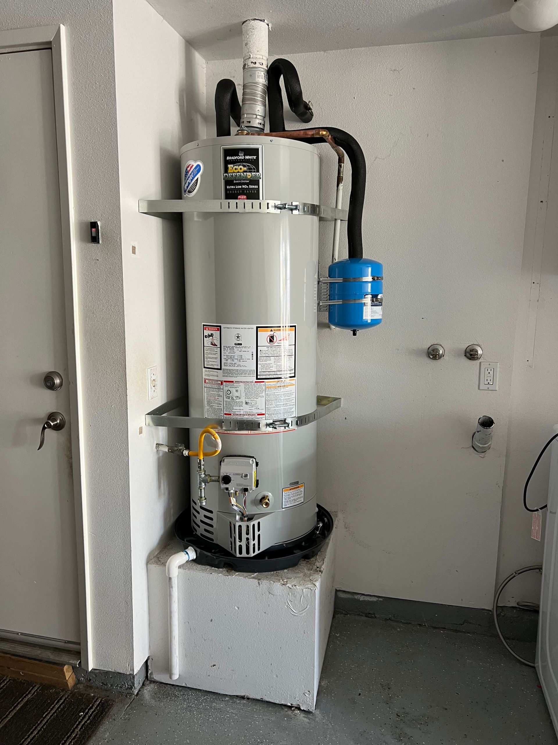 A water heater is sitting on top of a white box in a room.