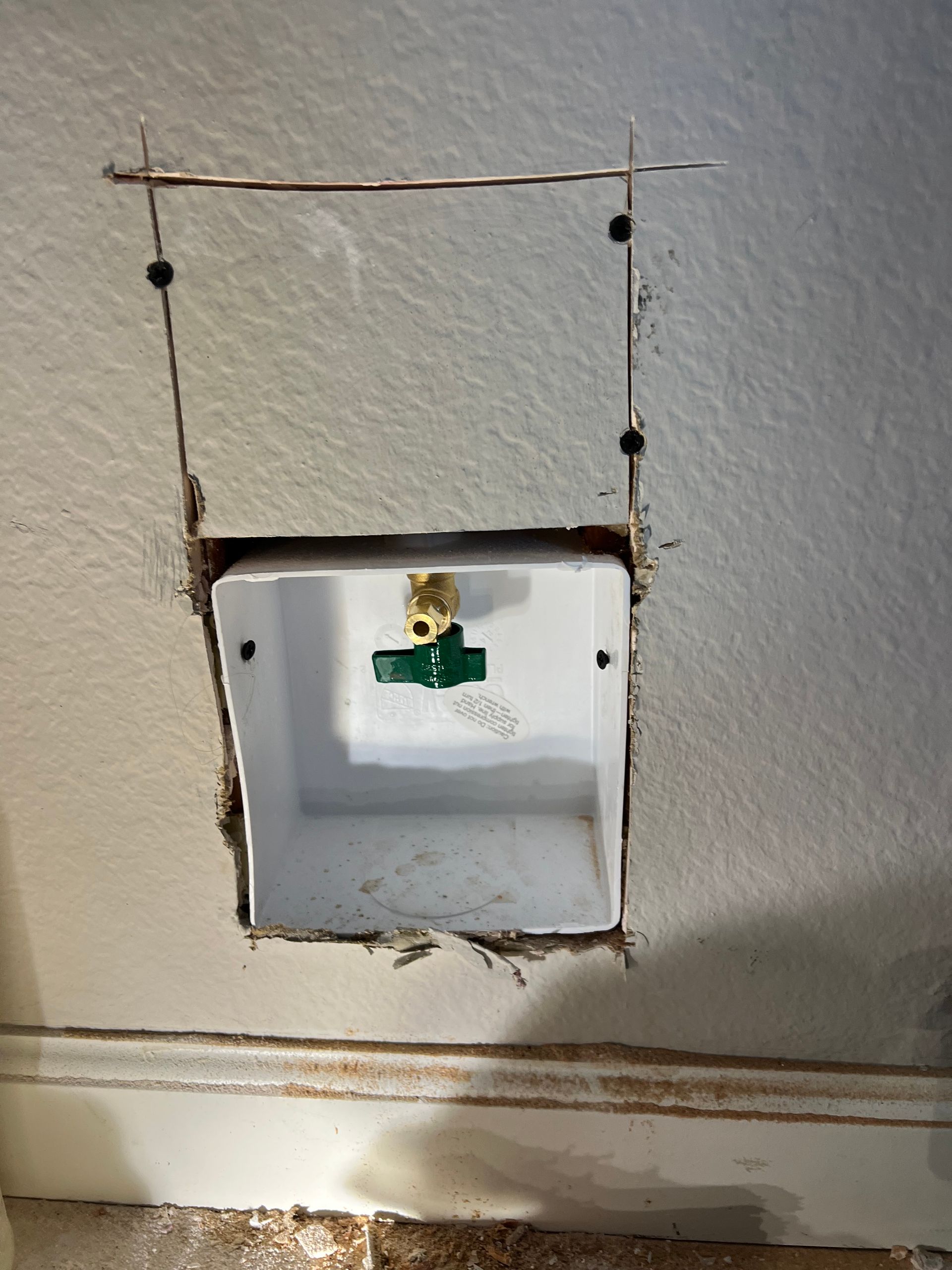 White washing machine water valve box in wall, with water valve and cut lines.