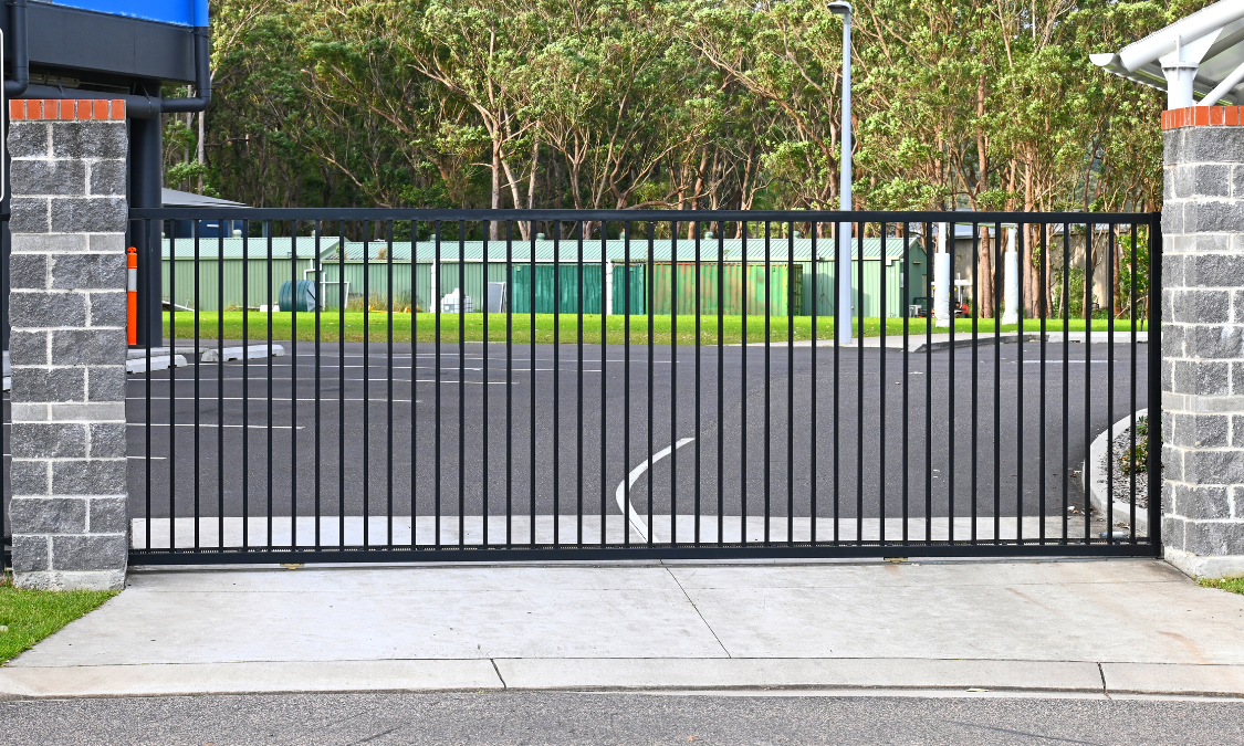 Ornate black metal gate with decorative peaks, between stone pillars.