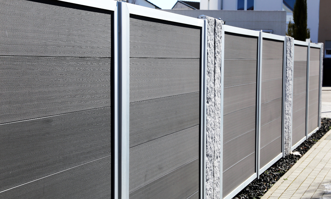 Wooden fence enclosing a concrete patio, blue sky, white cloud.