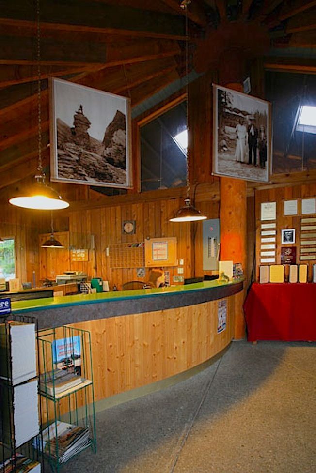 Interior of a visitor center with a curved wooden counter, photos on the wall, and hanging pendant lights.