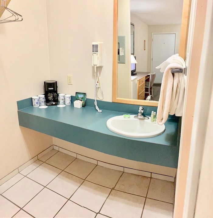 Bathroom vanity with a blue countertop, white sink, and mirror. White towels hang on a rack.