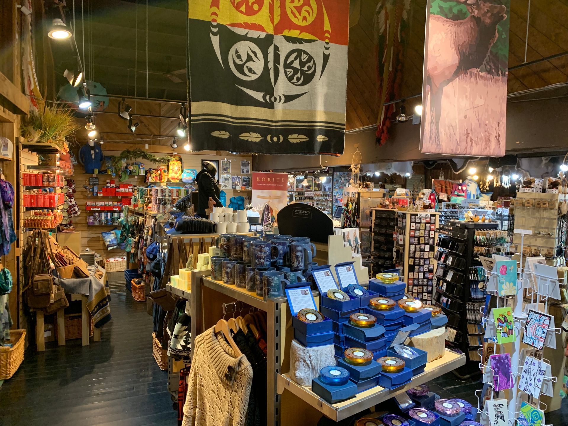 Inside a retail shop: products on shelves, tribal art banners hanging.