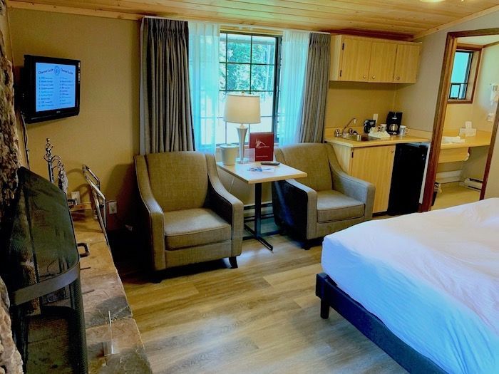 Cozy hotel room with two armchairs, a small table, a bed, and a window.