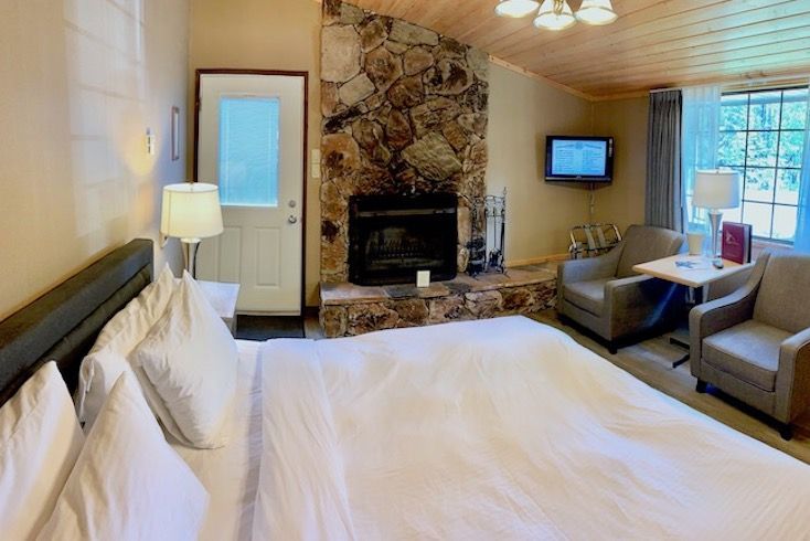 Bedroom with fireplace, king-sized bed, two armchairs, small TV, and an exterior door.