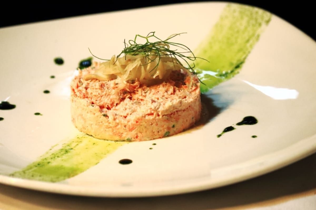 Plate of food: cylindrical pink dish with green sauce and garnish.