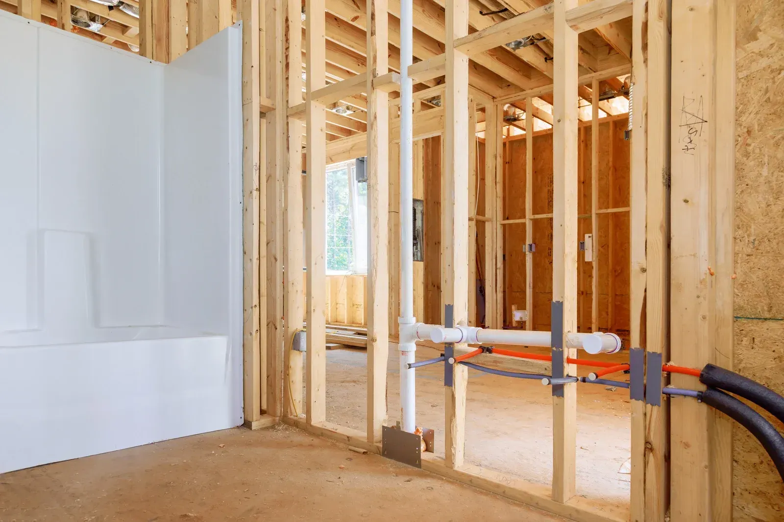 A bathroom in a house under construction with wooden beams and pipes.