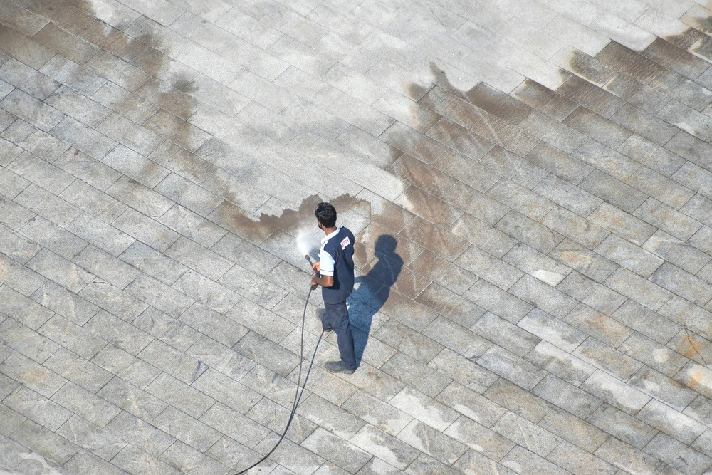 a man is cleaning a brick pavement with a high pressure washer .