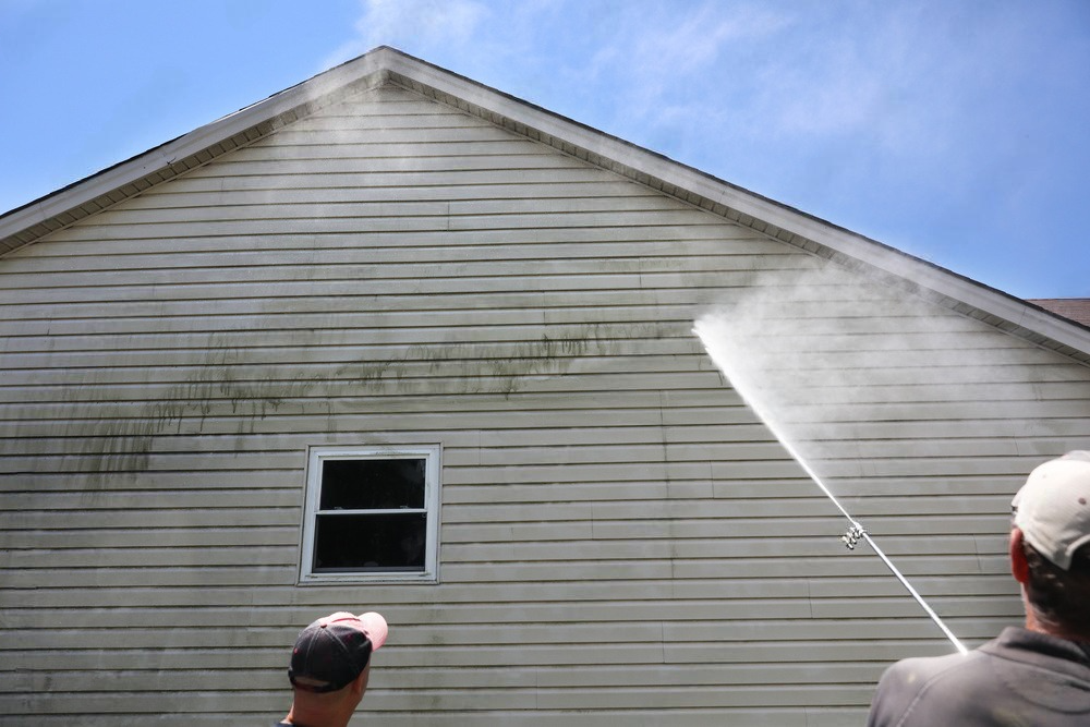 a man is spraying a house with a high pressure washer .