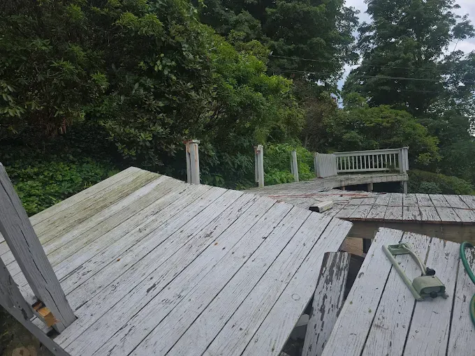 Dilapidated wooden deck with a view of trees and a small platform.