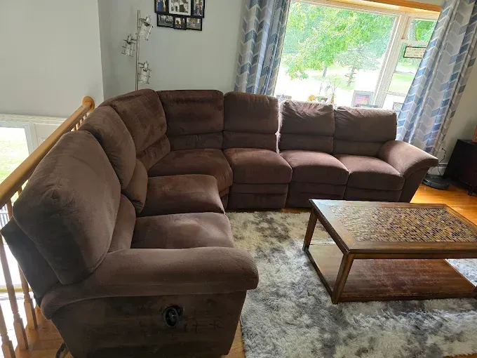 Brown sectional sofa in a living room with a wooden coffee table and a window.