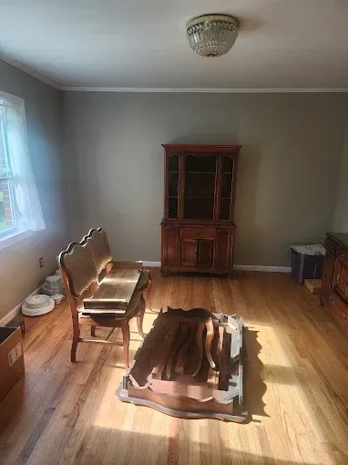 Empty room with hardwood floors, a wooden hutch, bench, and a coffee table covered by hide.