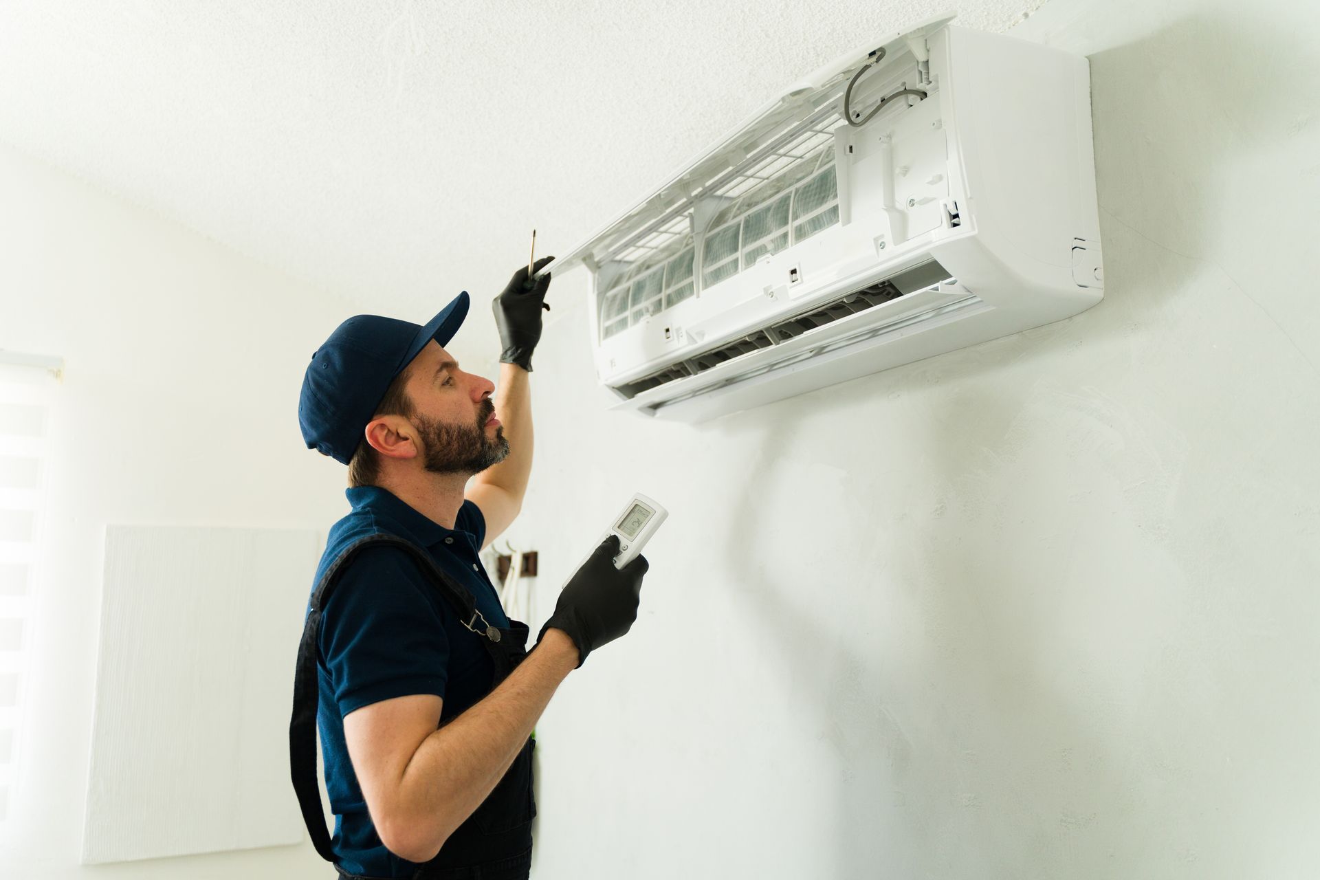 Air conditioning contractor inspecting wall-mounted AC unit. Air conditioning contractor inspecting wall-mounted AC unit.