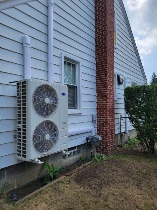 A mini split condenser installed on the side of a house
