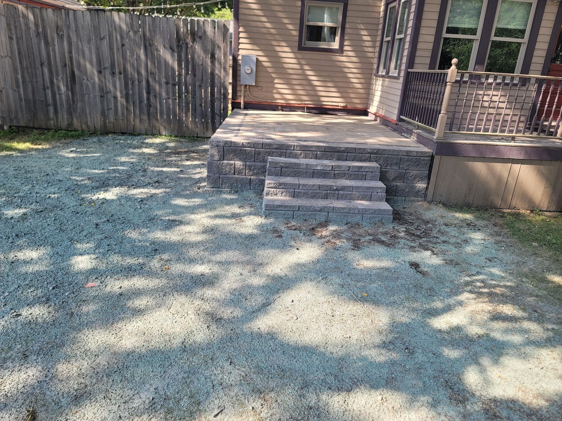 A house with stairs leading up to it and gravel in front of it.