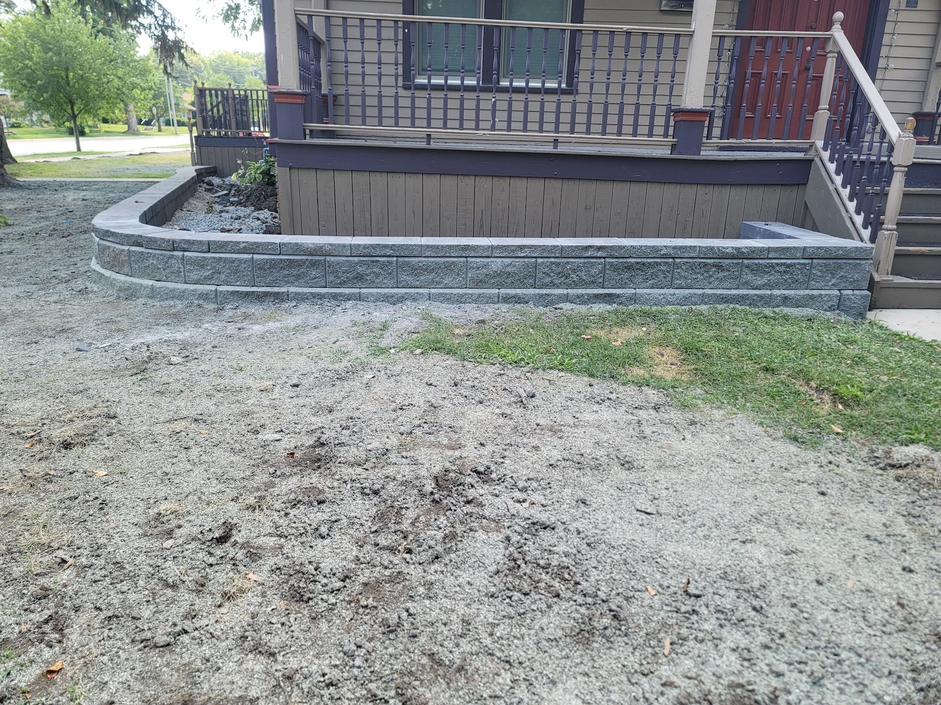 A stone wall is being built in front of a house.