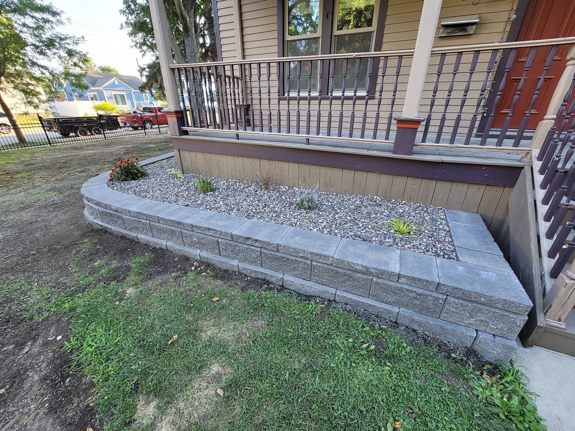A stone wall with a planter in front of a house.