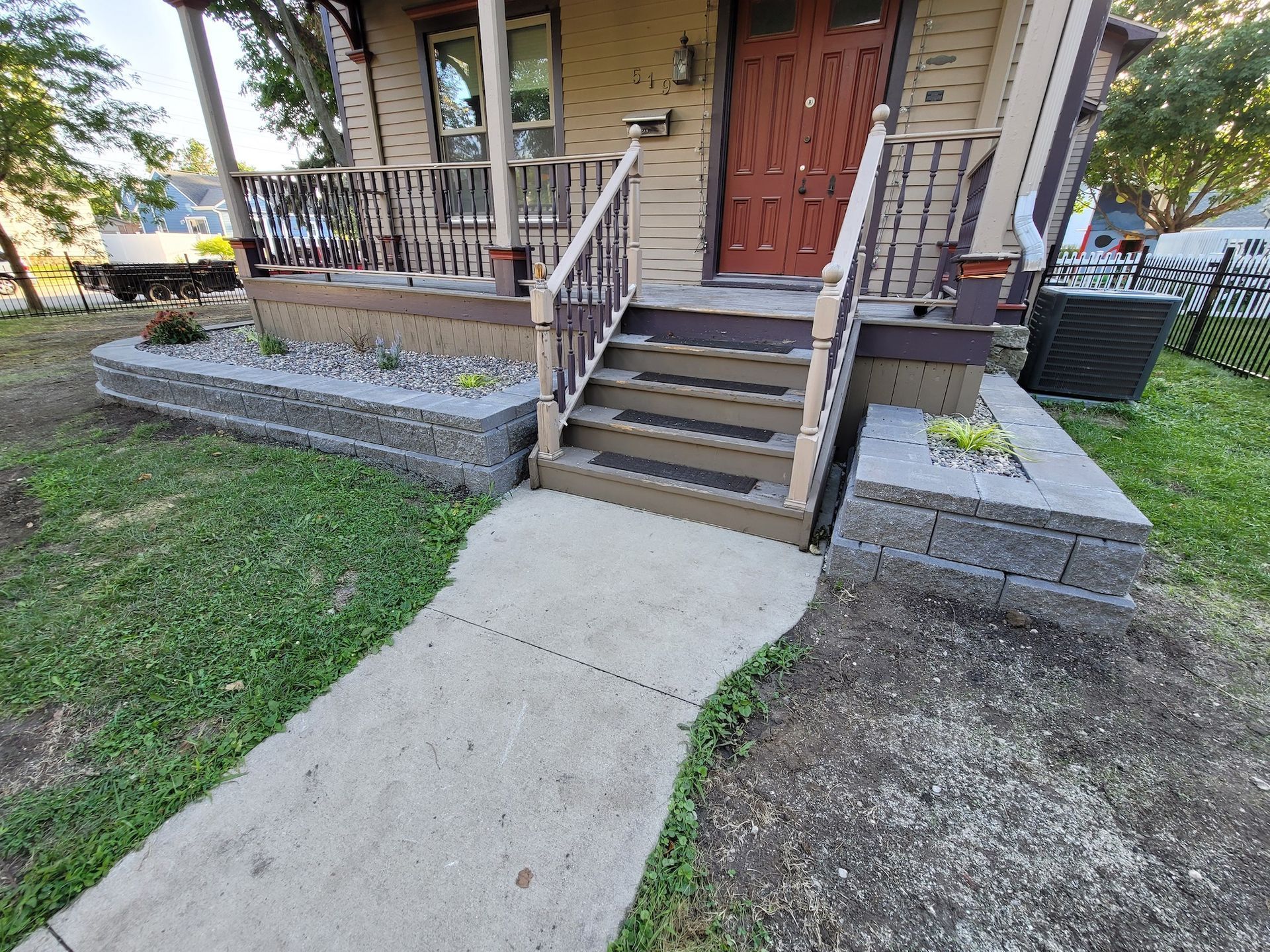 A house with a porch and stairs and a walkway leading to it.