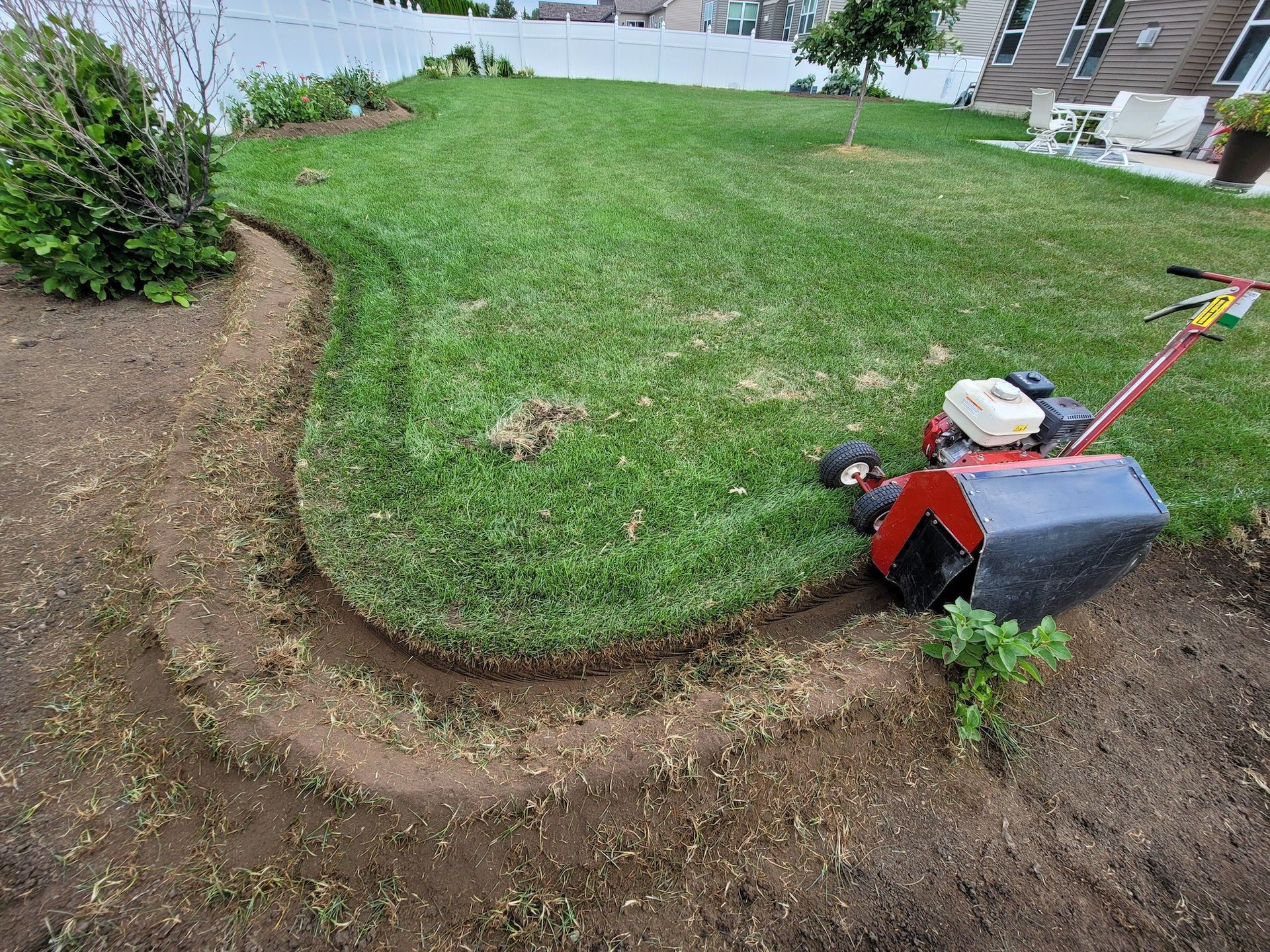 A lawn mower is cutting the grass in a backyard.
