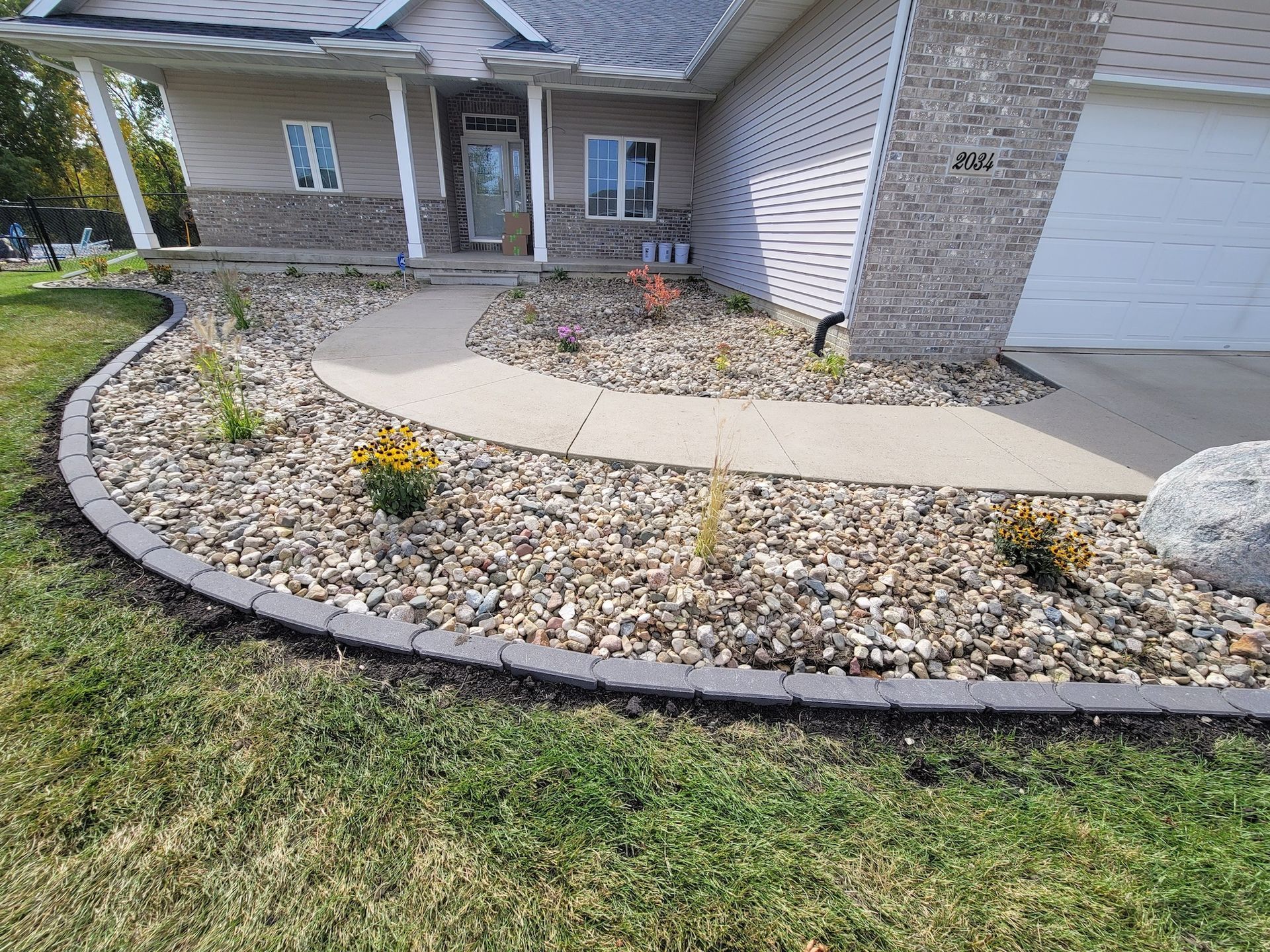 A house with a walkway and a gravel garden in front of it.