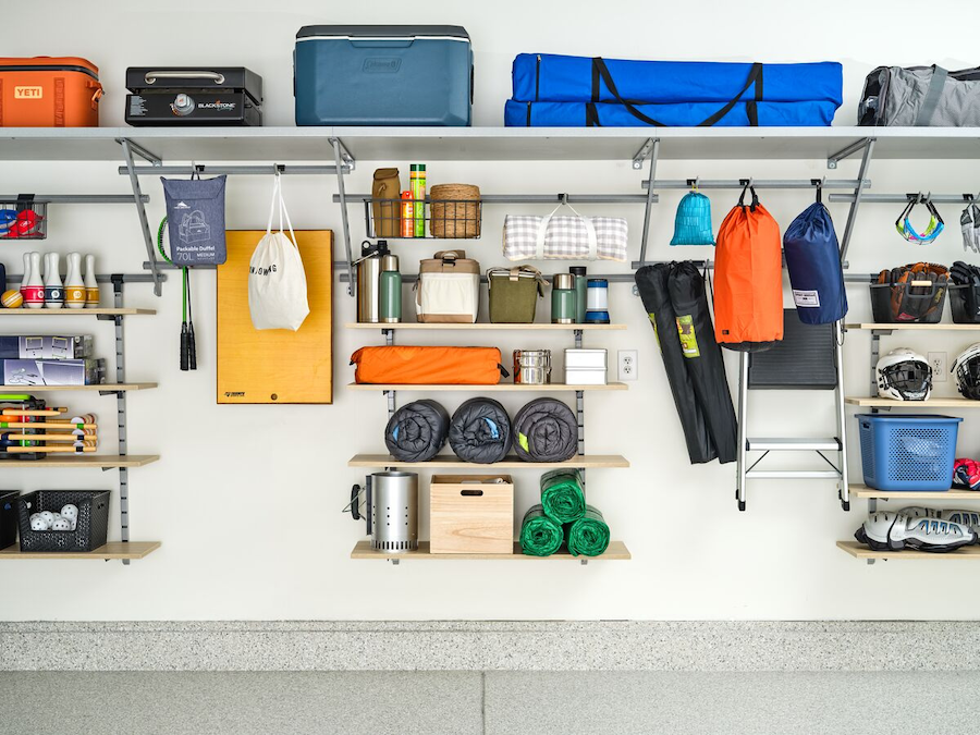 Organized garage space featuring shelving, storage bins, and hooks for outdoor gear, and tools.