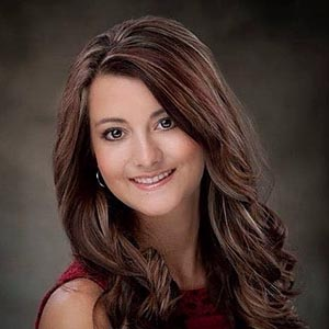 A woman with long brown hair is smiling for the camera.