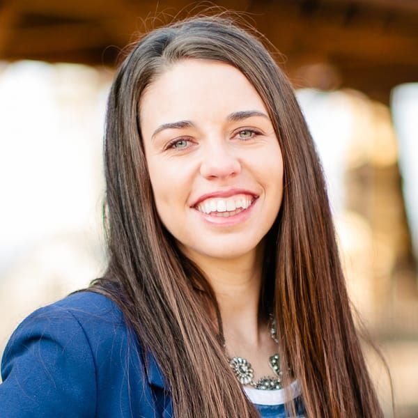 A woman with long hair is smiling and wearing a blue jacket.